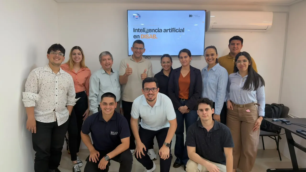 El equipo de DISAB Paraguay junto a Diego Ceredi frente a la pantalla «Inteligencia artificial en DISAB», al cierre de la capacitación en Gemini para empresas, Lambaré, octubre de 2026